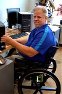 Randy seated in his wheelchair at computer work bench
